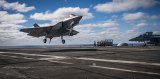 A Navy F-35 lands on an aircraft carrier.